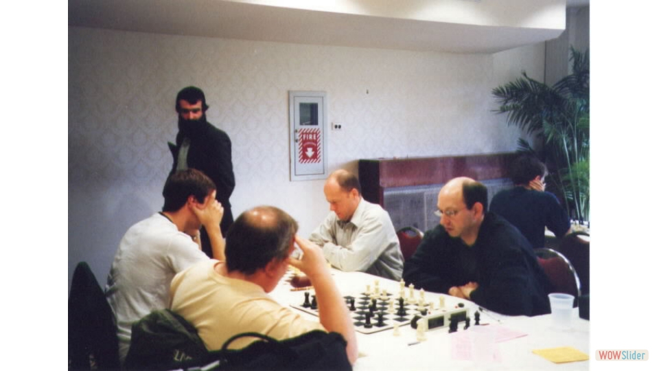 FM Igor Nikolayev vs GM Alexander Stripunsky at NY State Championship, Kerhonkson, NY, 2002. GM Joel Benjamin vs IM Jay Bonin in front. GM Leonid Yudasin watching.